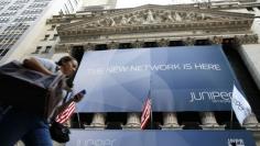 A woman walks past a banner with the logo of Juniper Networks Inc. covering the facade of the New York Stock Exchange, October 29, 2009.  REUTERS/Brendan McDermid 