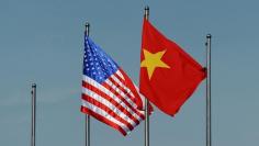 FILE PHOTO: The U.S. flag (L) flutters next to the Vietnamese flag during a welcoming ceremony for U.S. Defense Secretary Ash Carter (not pictured) at the Defense Ministry in Hanoi, Vietnam June 1, 2015. REUTERS/Hoang Dinh Nam/Pool